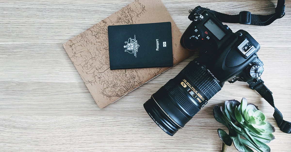 Flat lay of a camera, passport and travel journal